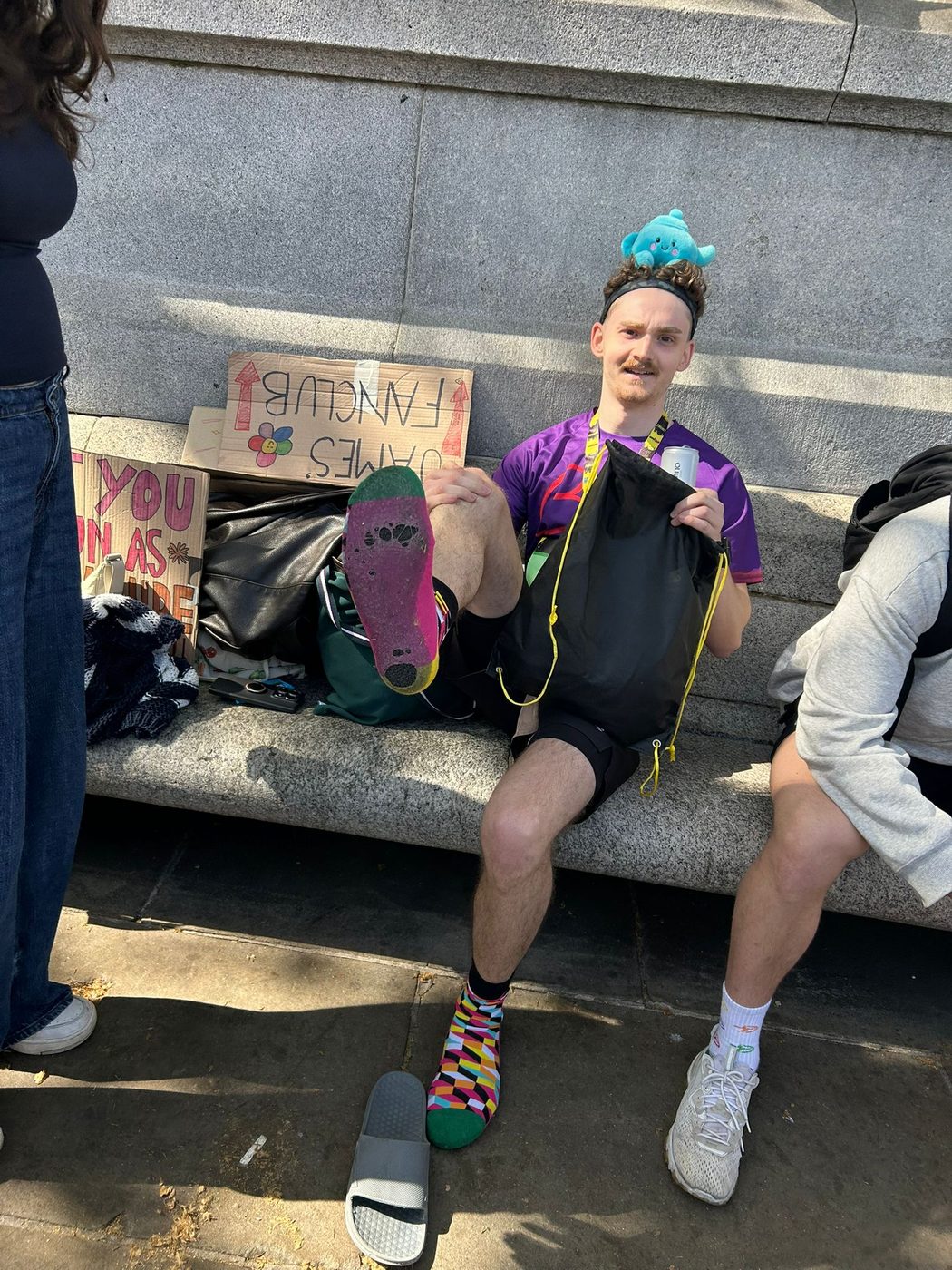 Sitting on a bench with friends, holding up the sole of a shoe